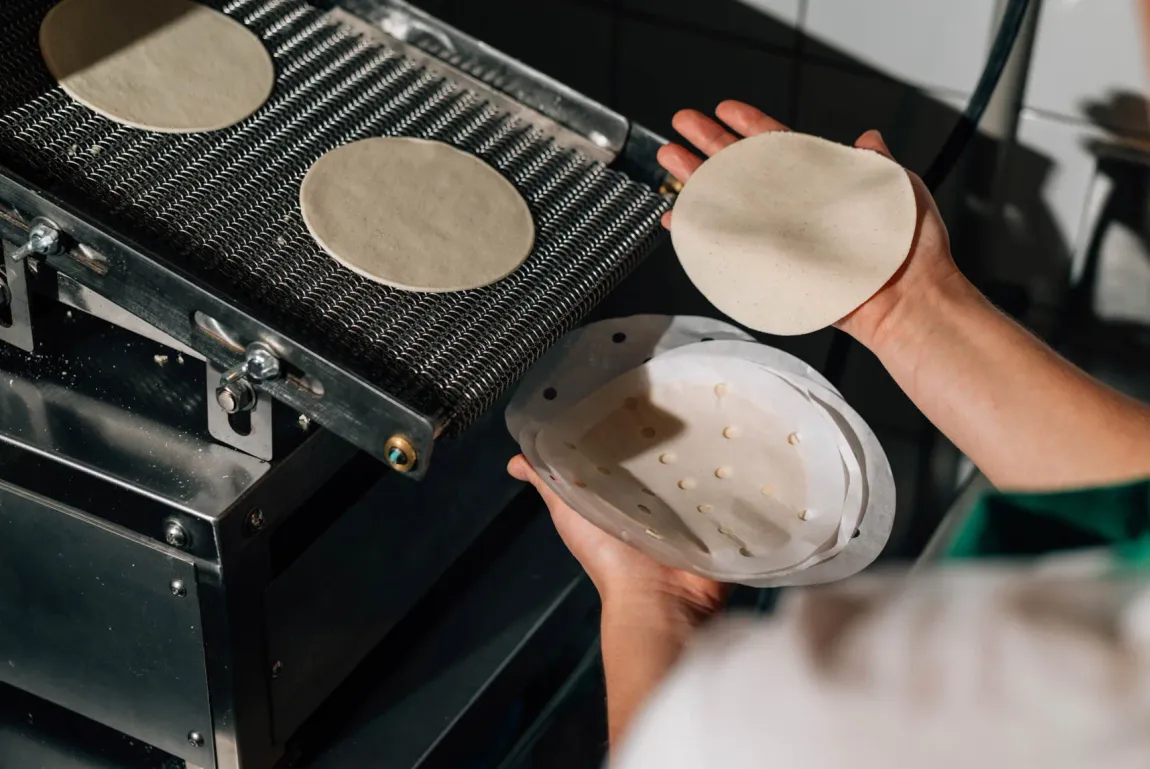 Fresh corn tortillas coming off the press
